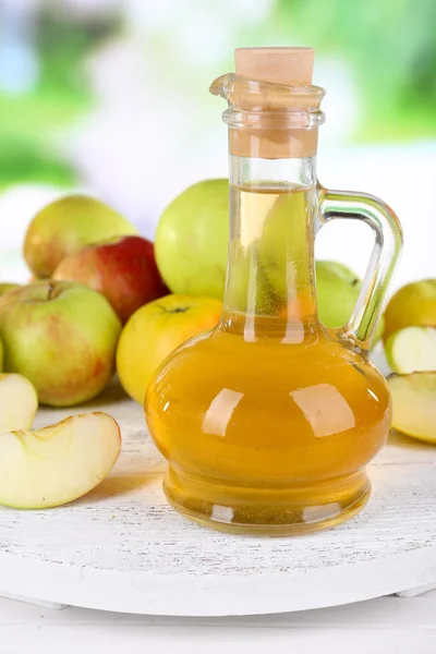 Vinagre de sidra de manzana en botella de vidrio y manzanas frescas maduras, sobre mesa de madera, sobre fondo natural —  Fotos de Stock