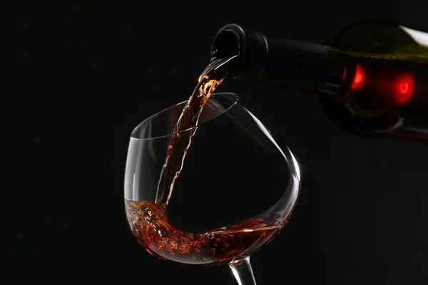 Vinho tinto derramando em copo de vinho, close-up — Fotografia de Stock