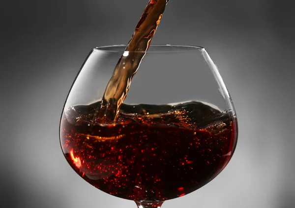 Vinho tinto derramando em copo de vinho, close-up — Fotografia de Stock