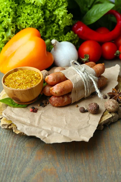 Composition of thin sausages, mustard in bowl and spices on cutting board, on wooden background — Stock Photo, Image