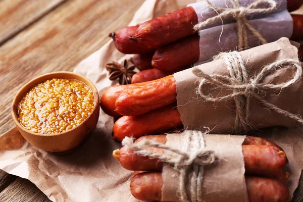 Assortiment de saucisses fines et d'épices sur papier, sur fond de bois — Photo