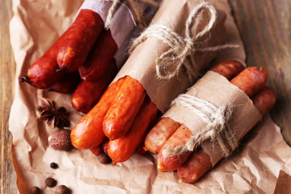 Assortiment de saucisses fines et d'épices sur papier, sur fond de bois — Photo