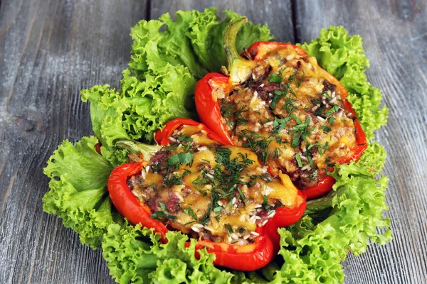 Stuffed red peppers with greens on plate on wooden table — Stock Photo, Image