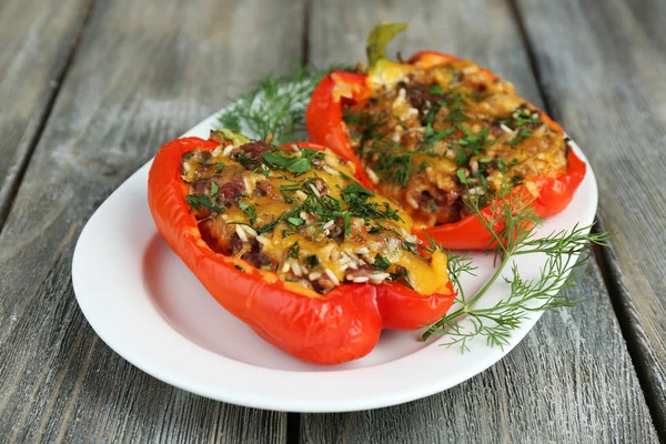 Stuffed red peppers with greens on plate on wooden table — Stock Photo, Image