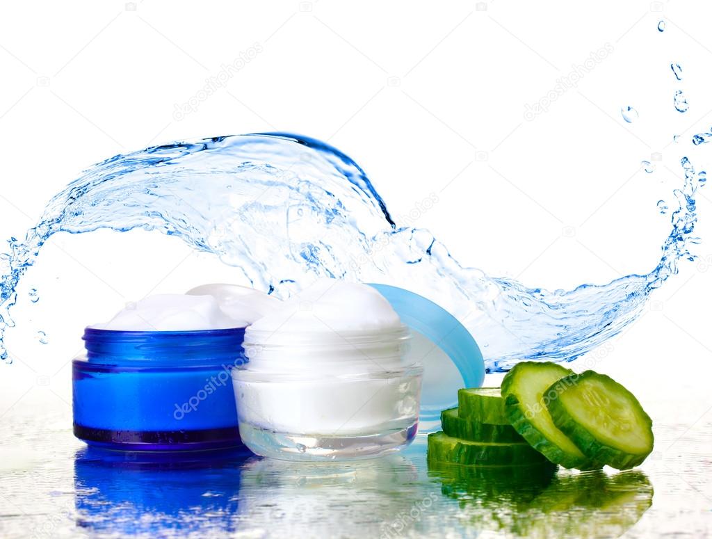 Cream and fresh sliced cucumber on mirror surface on abstract water splashing background