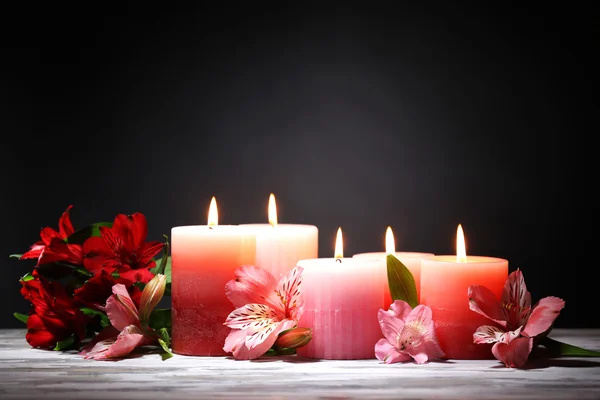 Belas velas com flores na mesa de madeira, no fundo escuro — Fotografia de Stock