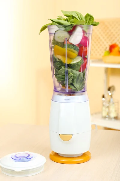 Blender with fresh vegetables on kitchen table