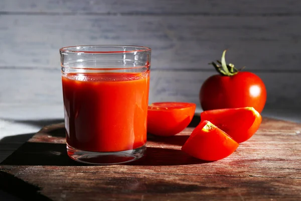 Verre de jus de tomate avec des épices et des tomates fraîches sur une table en bois. Avec fond sombre — Photo