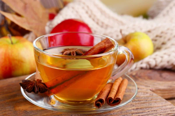 Composición de sidra de manzana con varillas de canela, manzanas frescas, bufanda tibia y hojas de otoño sobre fondo de madera — Foto de Stock