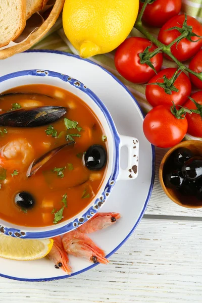Sopa saborosa com camarões, mexilhões, tomates e azeitonas pretas em tigela sobre fundo de madeira — Fotografia de Stock