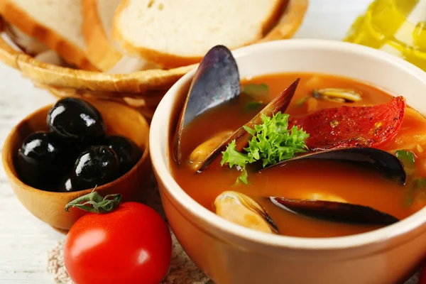 Γευστική σούπα με γαρίδες, μύδια, ντομάτες και μαύρες ελιές σε μπολ σε ξύλινα φόντο — Φωτογραφία Αρχείου
