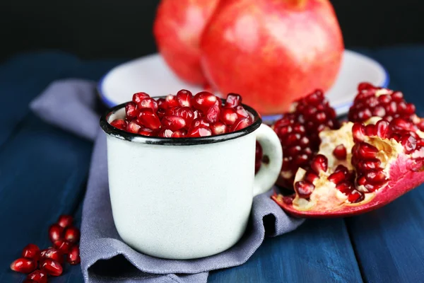 Juicy ripe pomegranate on wooden table, on dark background — Stock Photo, Image