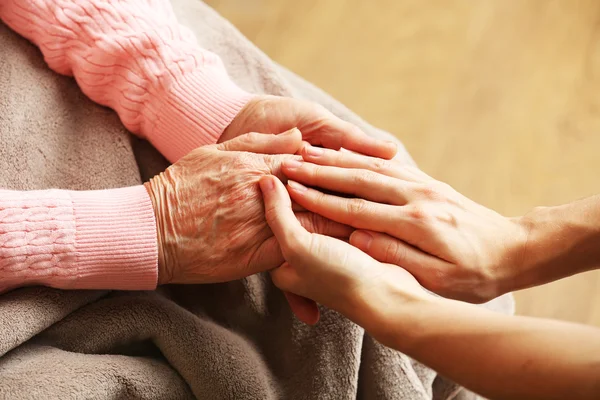 Old and young holding hands on light background — Stock Photo, Image