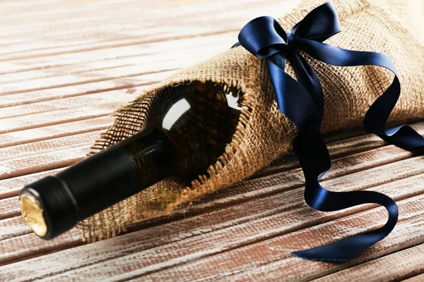 ワインのボトルに包まれた木の板の背景に黄麻布 — ストック写真