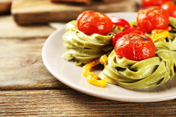 Pâtes vertes savoureuses au poivre et tomates sur fond de table en bois — Photo