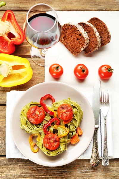 Pâtes savoureuses au poivre, carotte et tomates sur fond de table en bois — Photo