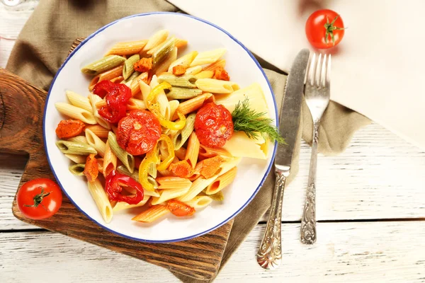 Pasta salad with pepper, carrot and tomatoes on wooden table background — Stock Photo, Image