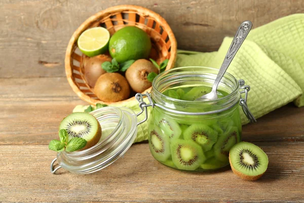 Smakelijke kiwi jam in glazen pot op houten achtergrond — Stockfoto