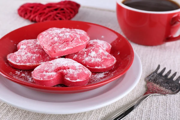 Cookies in vorm van hart op plaat met kop koffie op servet en kleur houten planken achtergrond — Stockfoto