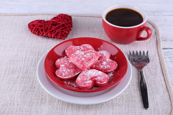 Cookies in vorm van hart op plaat met kop koffie op servet en kleur houten planken achtergrond — Stockfoto