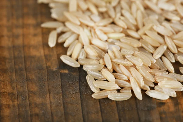 Grãos de arroz sobre fundo de madeira — Fotografia de Stock