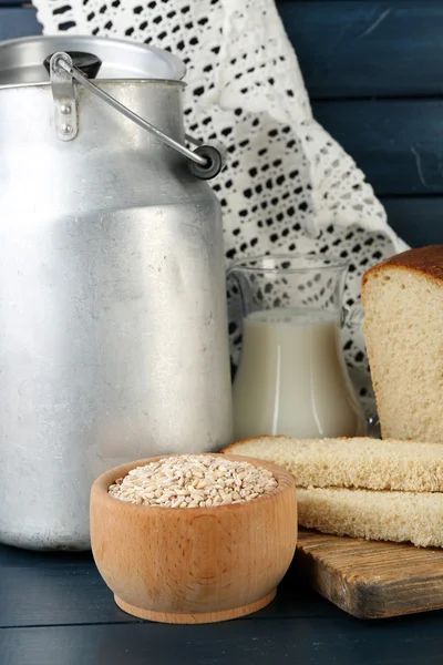 Retro can for milk with fresh bread and glass jug of milk on wooden background. Bio products concept