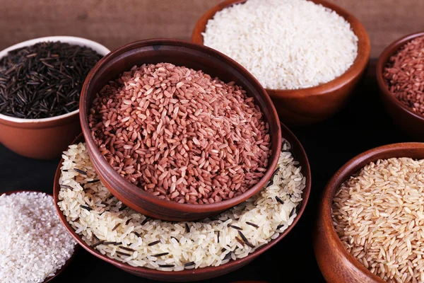 Různé druhy rýže v misky na stole na pozadí pytloviny — Stock fotografie