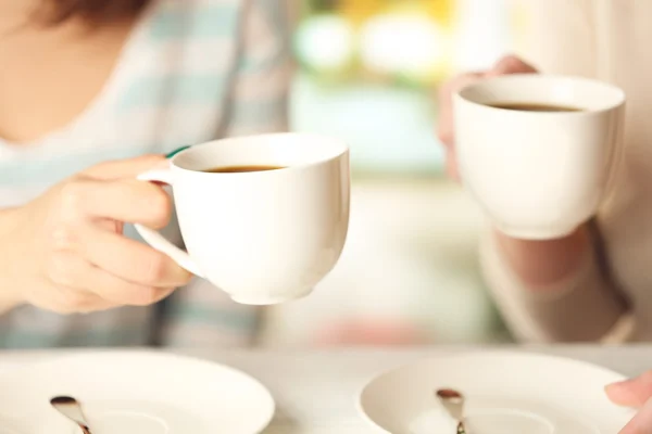 Dos mujeres con tazas de café sobre fondo brillante — Foto de Stock