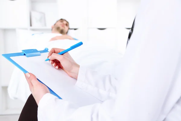 Médico llenando informe médico para su paciente de cerca — Foto de Stock