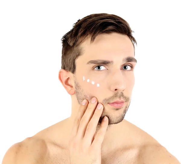 Hombre joven guapo aplicando loción crema en la cara aislada en blanco — Foto de Stock