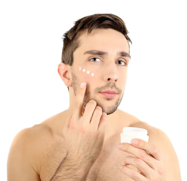 Hombre joven guapo aplicando loción crema en la cara aislada en blanco —  Fotos de Stock