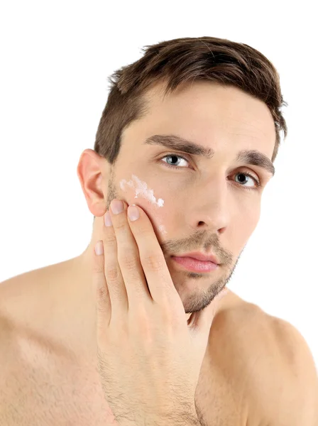 Hombre joven guapo aplicando loción crema en la cara aislada en blanco —  Fotos de Stock