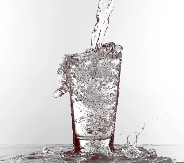 Agua vertiendo en vidrio aislado en blanco — Foto de Stock