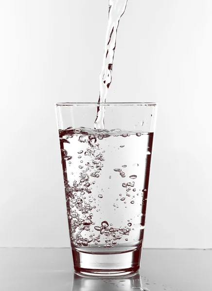 Wasser im Glas isoliert auf weiß gießen — Stockfoto