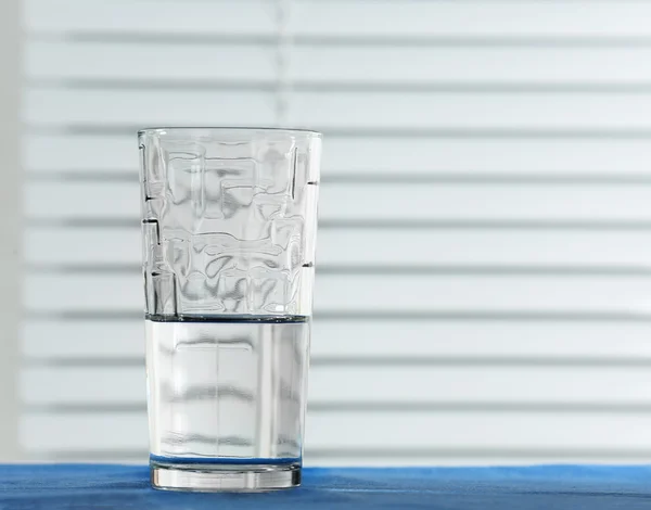 Bicchiere d'acqua sul tavolo su sfondo chiaro — Foto Stock