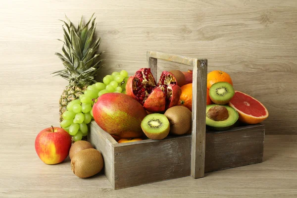 Sortimento de frutas exóticas em caixa no fundo de madeira — Fotografia de Stock