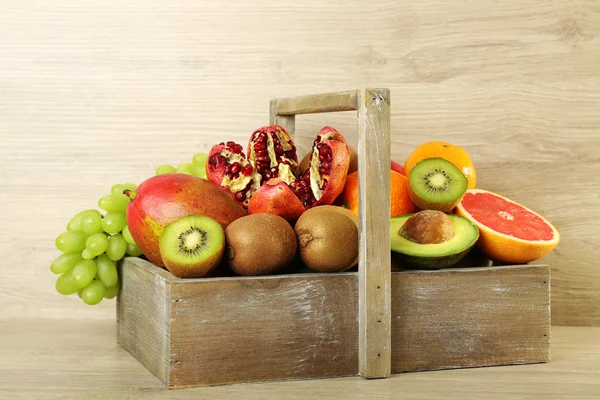 Assortment of exotic fruits in box on wooden background