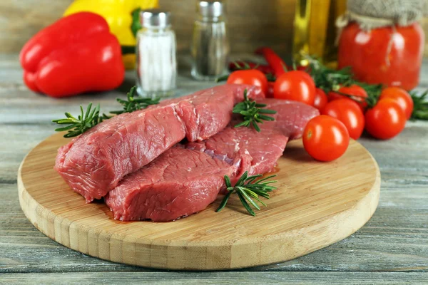 Bife cru na tábua de corte com legumes e especiarias no fundo de madeira — Fotografia de Stock