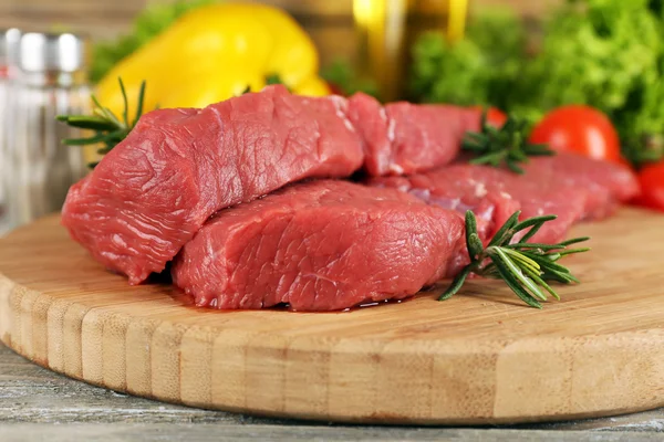 Bistecca di manzo cruda sul tagliere con verdure e spezie su fondo di legno — Foto Stock