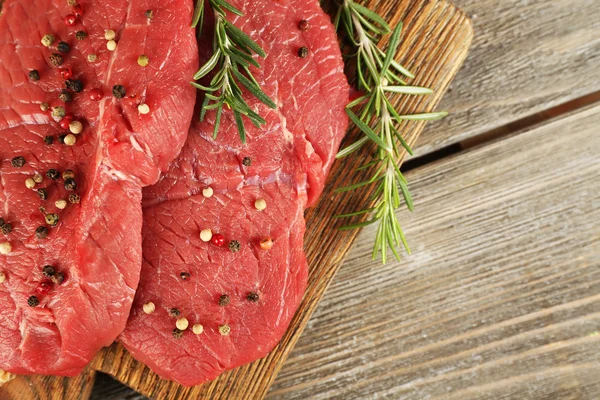 Syrové hovězí steak s rozmarýnem a koření na prkénko na dřevěné pozadí — Stock fotografie