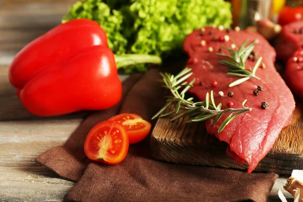 Rohes Rindersteak mit Gewürzen und Gemüse auf dem Tisch aus nächster Nähe — Stockfoto