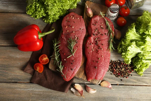 Raw beef steak with spices and greens on table close up — Stock Photo, Image