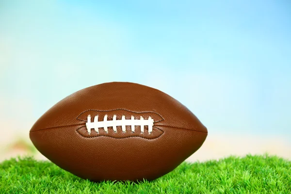 American football on field on green grass, on blue sky background