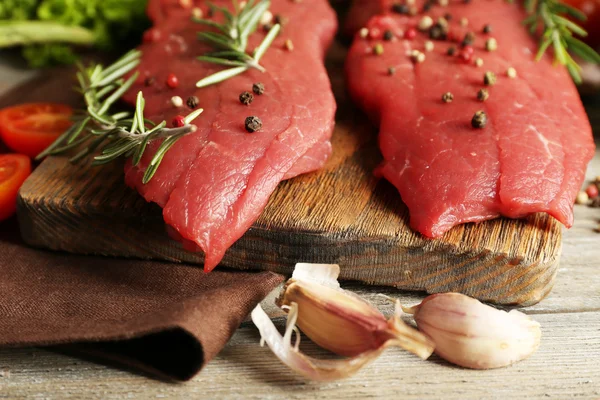 Raw beef steak with spices and greens on table close up — Stock Photo, Image