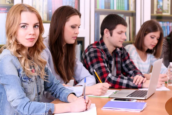 Grupo de estudantes sentados à mesa na biblioteca — Fotografia de Stock