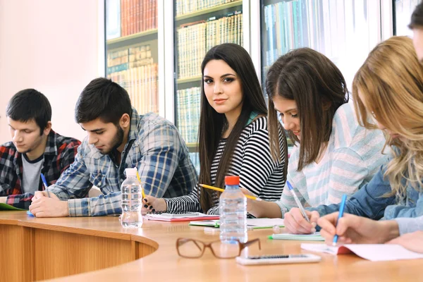 Skupina studentů sedících u stolu v knihovně — Stock fotografie