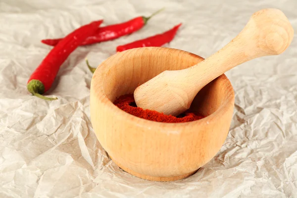 Gemalen rode peper in mortel met chili peper op tafel close-up — Stockfoto