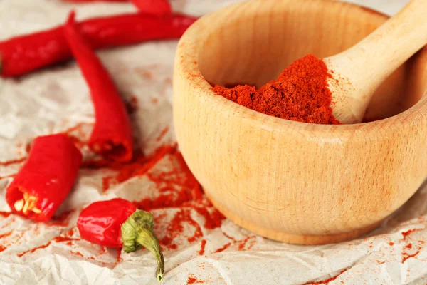 Ground red pepper in mortar with chili pepper on table close up — Stock Photo, Image