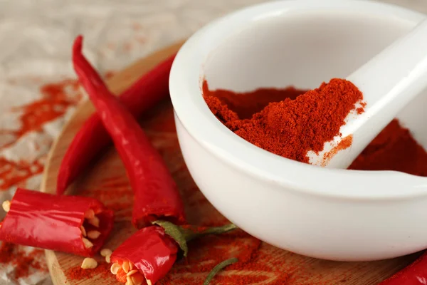 Ground red pepper in mortar with chili pepper on table close up — Stock Photo, Image