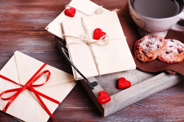 Liefdesbrieven met koffie en koekjes op houten achtergrond — Stockfoto